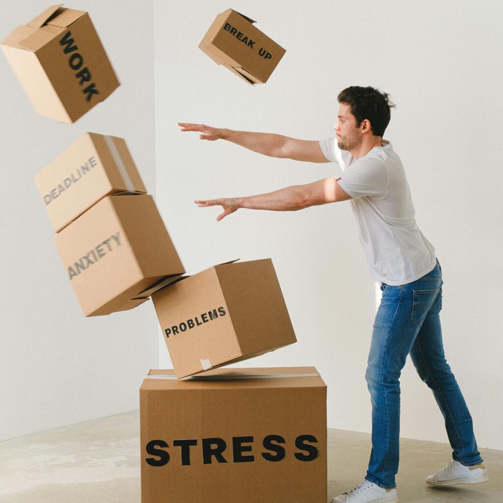 Full body of young man in sneakers and jeans pushing and falling boxes saying Work Problems Anxiety Stress and Deadline while fighting with problems